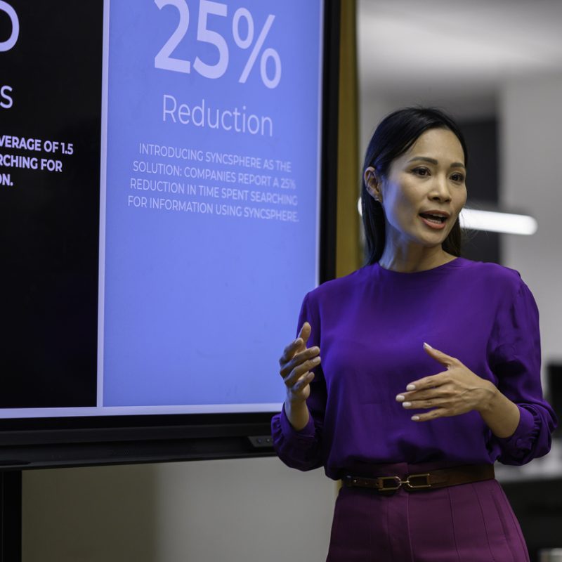 Businesswoman giving presentation on device screen during meeting.